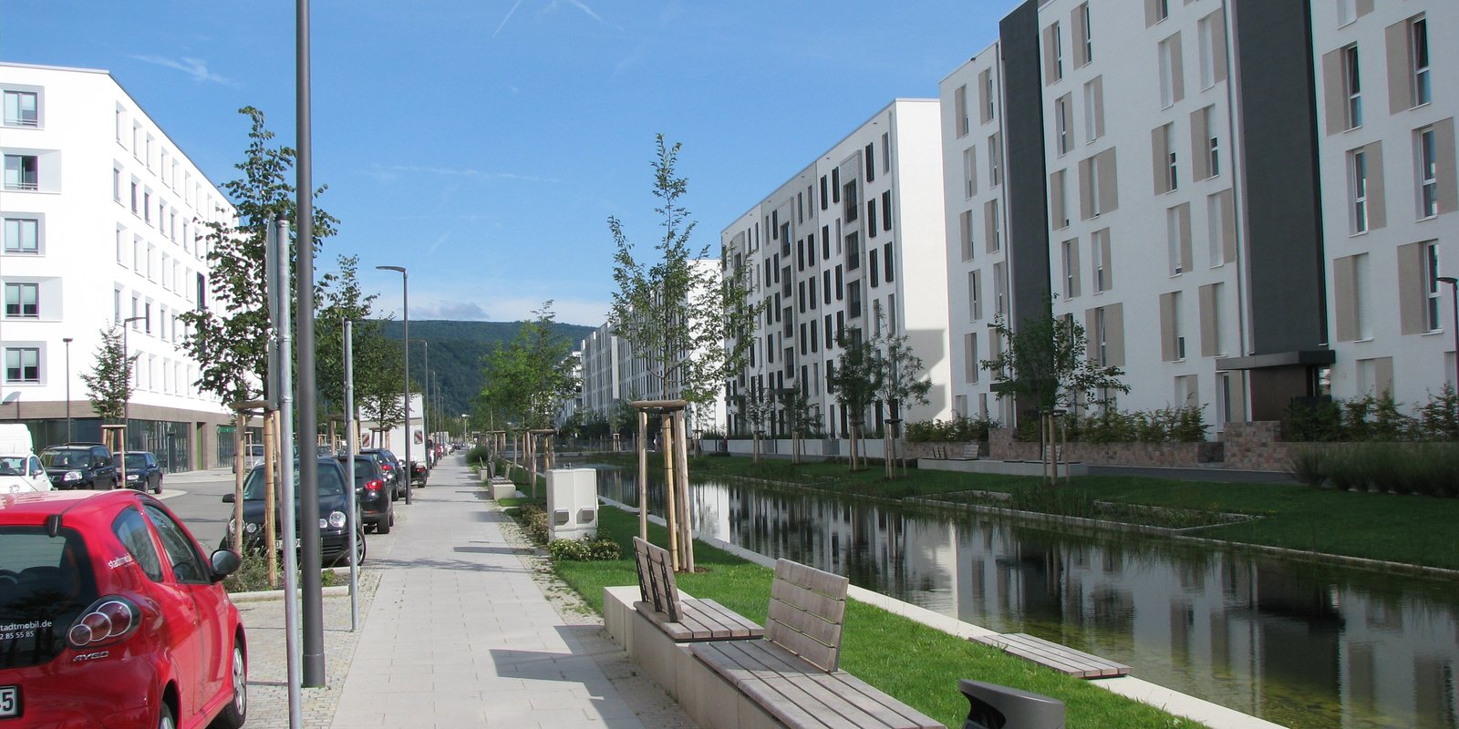 Der Lange Anger in der Heidelberger Bahnstadt mit Wasserlauf, Bäumen und moderner Wohnbebauung
